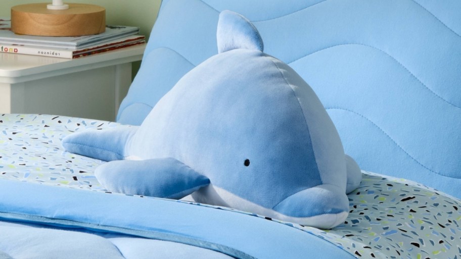 a blue dolphin weighted plush pillow on a bed