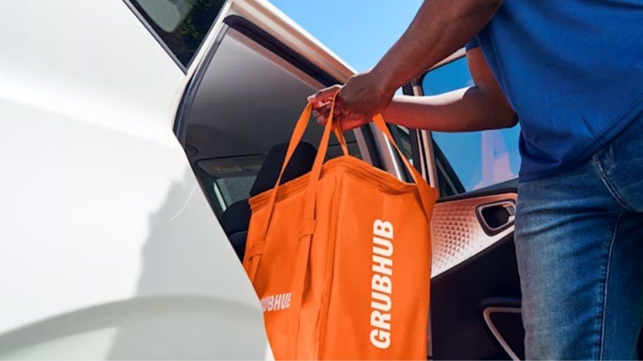 guy loading a grubhub into the seat of a car