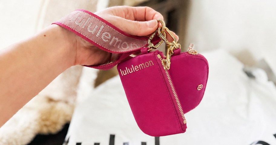 hand holding a pink dual pouch wristlet
