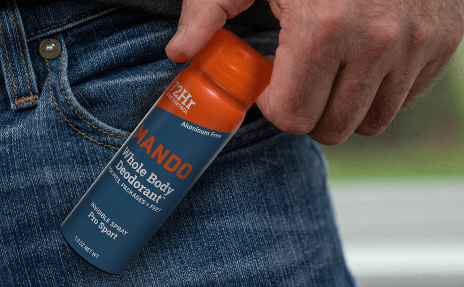 hand holding Mando spray deodorant 1 oz travel size next to jeans pocket