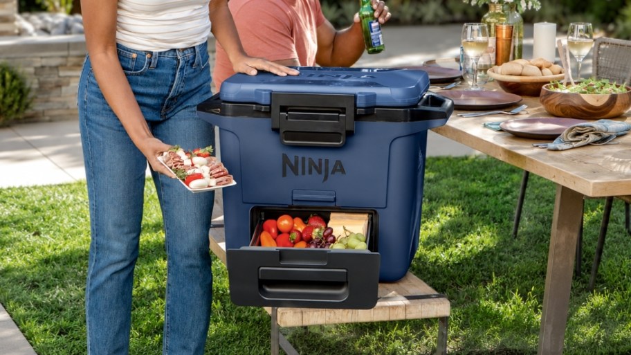 a woman removing a charcuterie tray from a hardside cooler