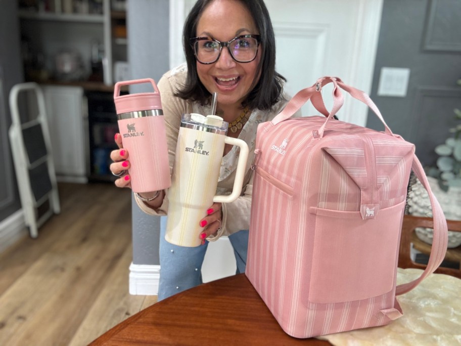 woman holding two tumblers next to pink cooler bag