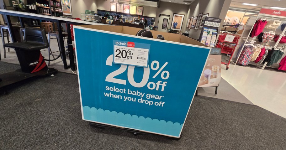 Large blue sign in a store offering 20% off select baby gear drop-offs. The store interior includes a coffee area and product displays.