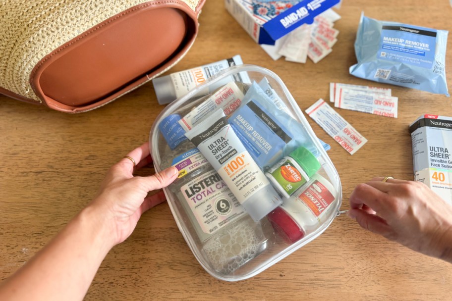 hand grabbing clear pouch with hygiene, beauty, and more products
