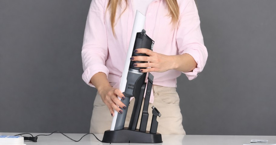 woman with a handheld vacuum on a charging stand