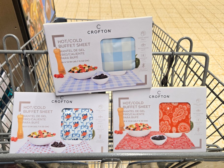 Three boxes of Crofton hot/cold buffet sheets in a shopping cart. Designs include blue checkered, floral, and red paisley.