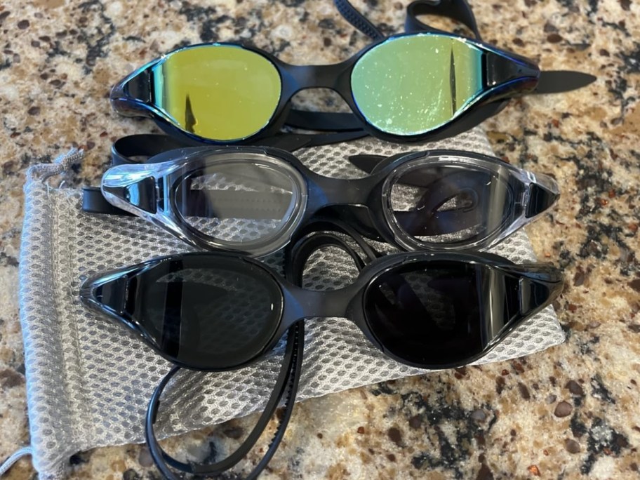 3 pairs of NSSIW Adult Swim Goggles sitting on kitchen counter with carrying case
