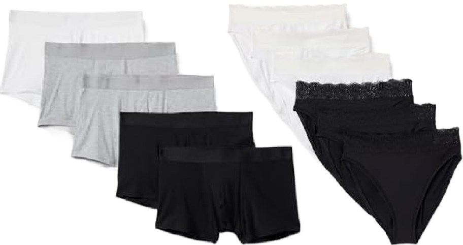 A collection of various underwear arranged in two groups. On the left, black, gray, and white boyshorts are neatly stacked. On the right, black and white bikini-cut panties with lace waistbands are layered.