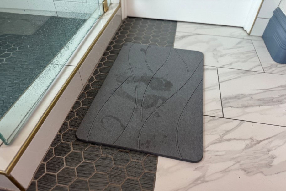 gray bath mat near shower with wet footprints