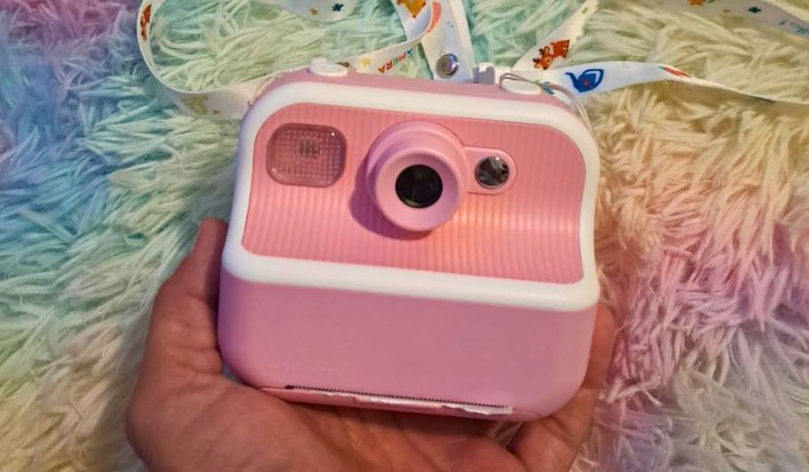 hand holding pink instant camera