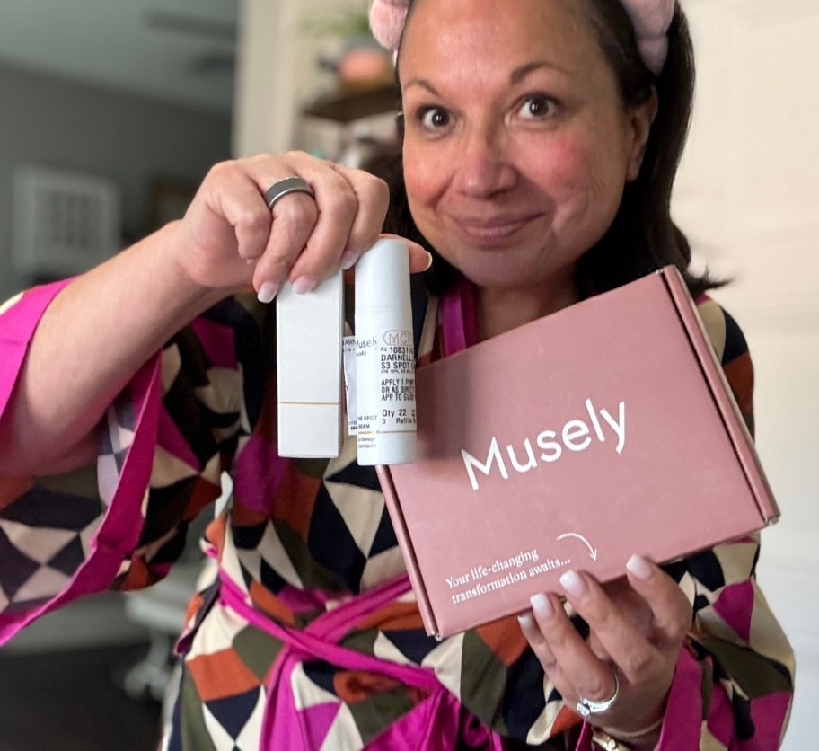 a woman holding a bottle of face cream and a shipping box