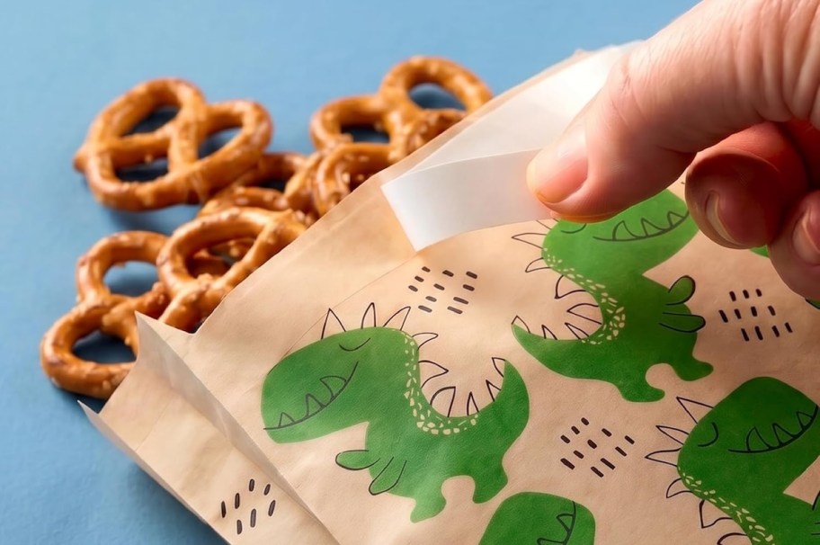 hand pulling sticker off tab on paper bag