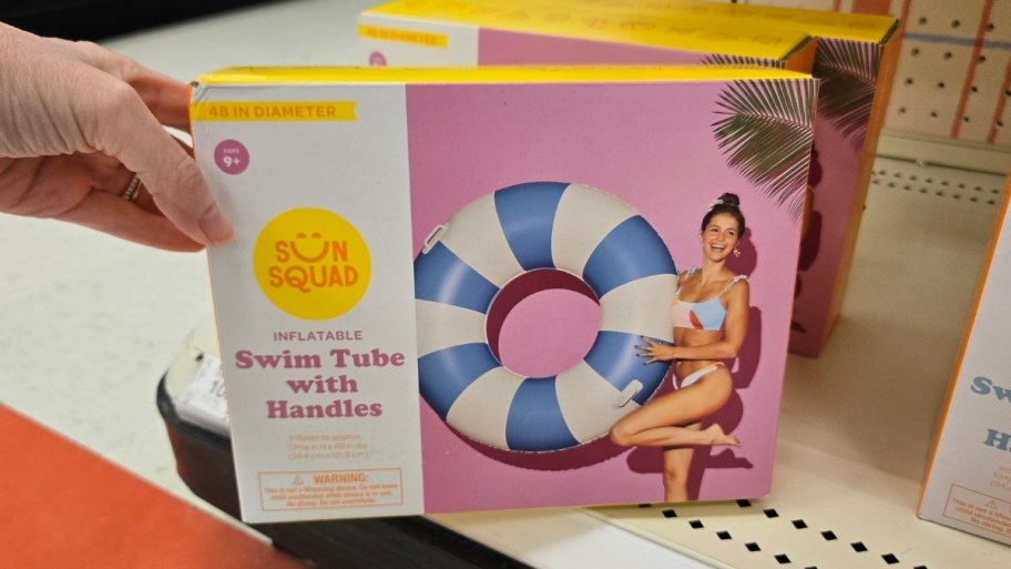 womans hand holding a sun squad swim tube
