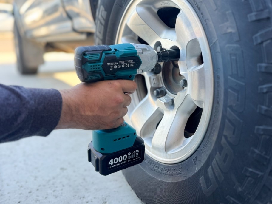 hand holding impact wrench and tightening lug nuts